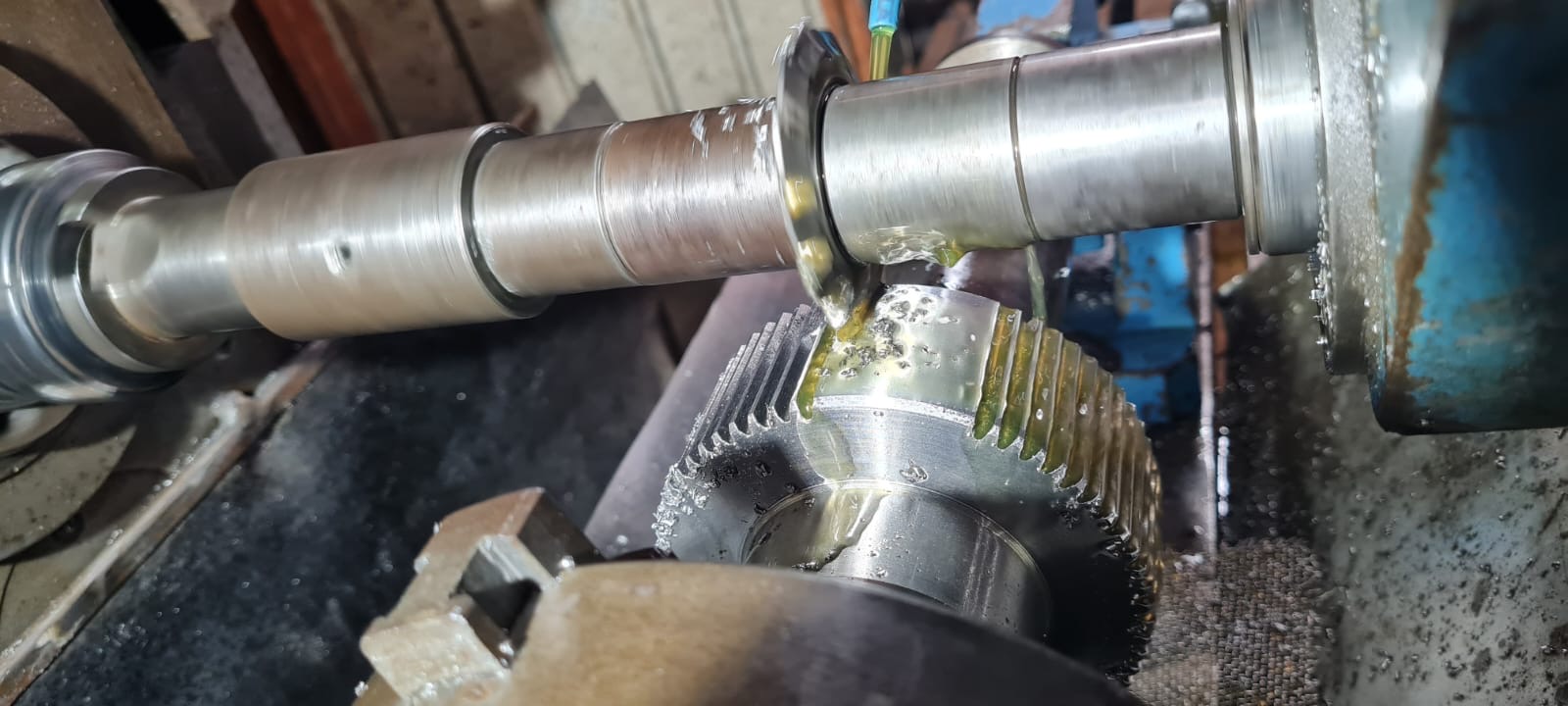 Engrenagem helicoidal sendo usinada em fresa na JS Tornearia, com refrigeração escorrendo pela peça